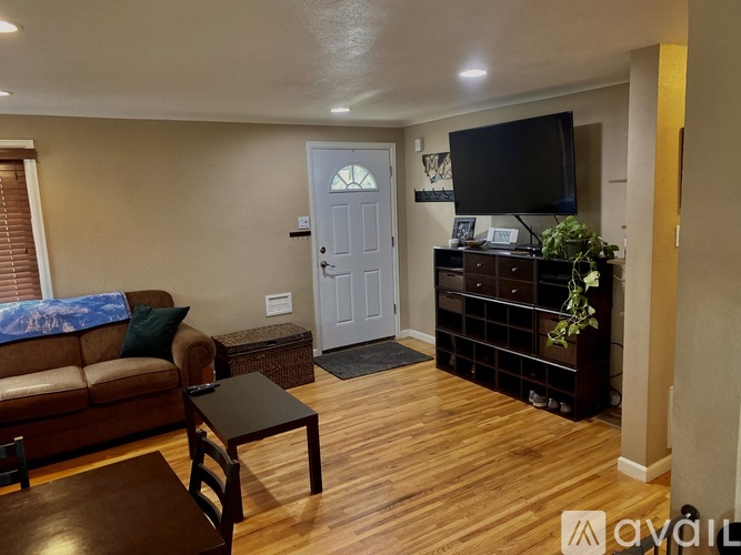 A living room with a brown couch, a black coffee table, and a flat screen TV mounted on the wall.