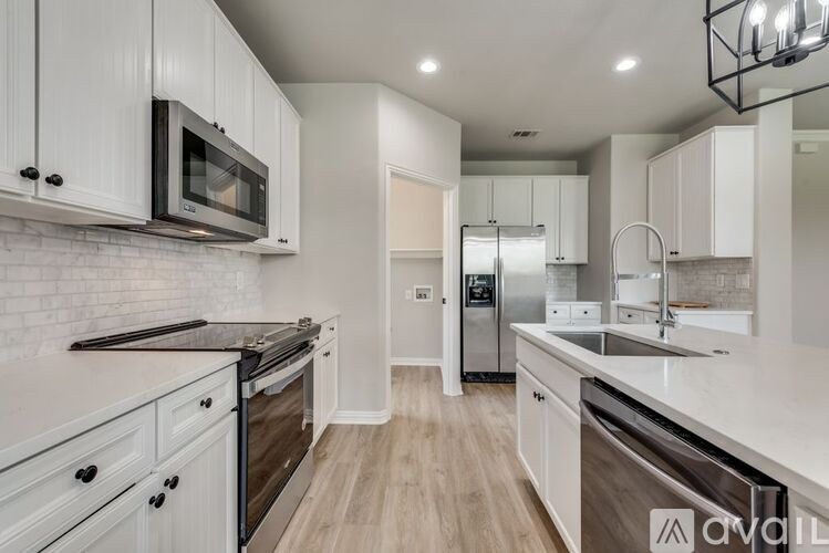 A modern kitchen with white cabinets and stainless steel appliances.