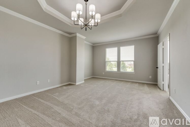 A spacious room with a chandelier and carpeted floor.