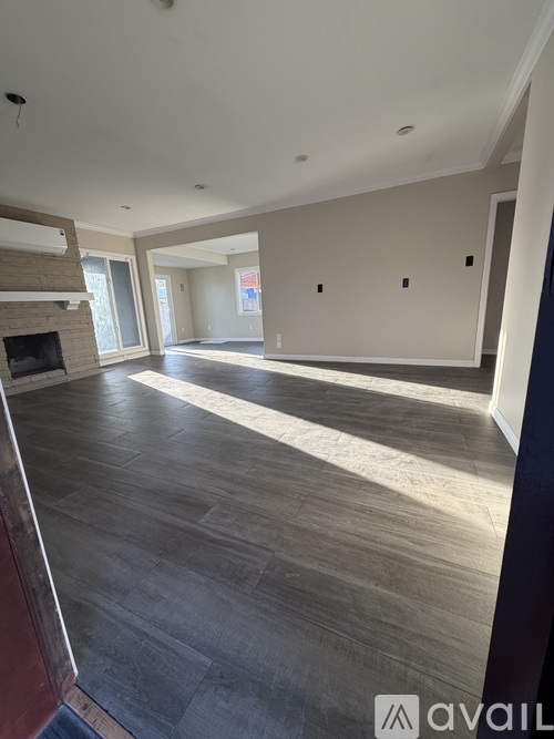 A spacious living room with a fireplace and wood flooring.
