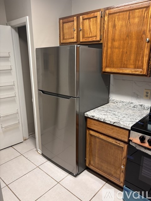 A kitchen with a refrigerator and wooden cabinets.