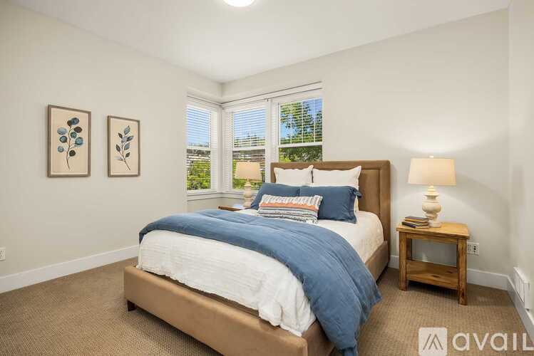 A bedroom with a large bed and a window with blinds.