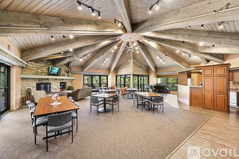 A large open living room with a stone fireplace and a dining table with chairs.