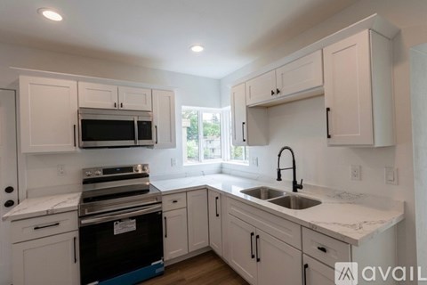 A kitchen with white cabinets and appliances is available for rent.