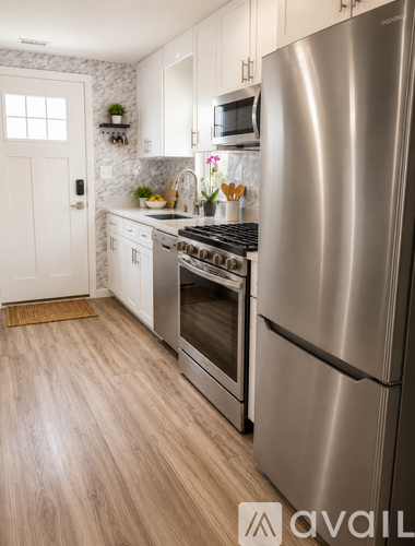 A kitchen with a stainless steel refrigerator and wooden flooring.