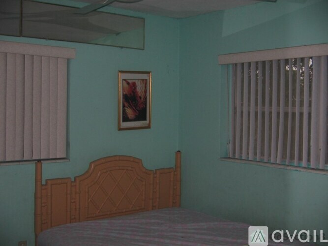A bedroom with a bed, a window with blinds, and a picture on the wall.