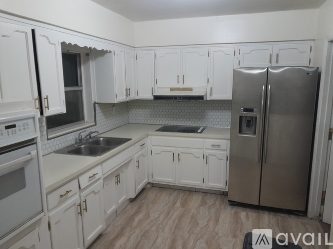 A kitchen with white cabinets and a stainless steel refrigerator.