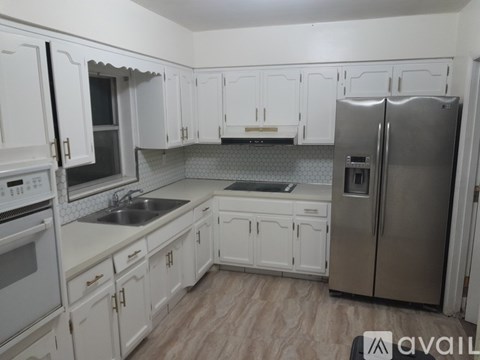 A kitchen with white cabinets and a stainless steel refrigerator.