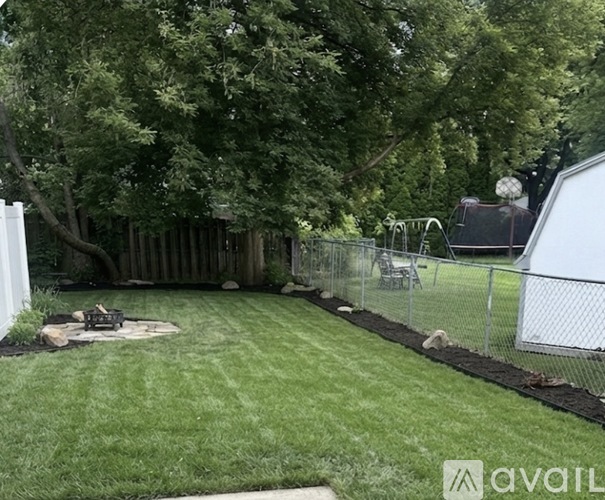 A backyard with a fence, a fire pit, and a playground.