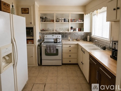 A kitchen with a white refrigerator and a white sink.