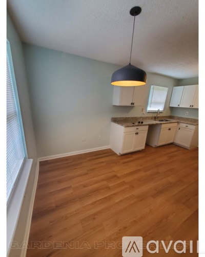 A kitchen with wooden floors and white cabinets.