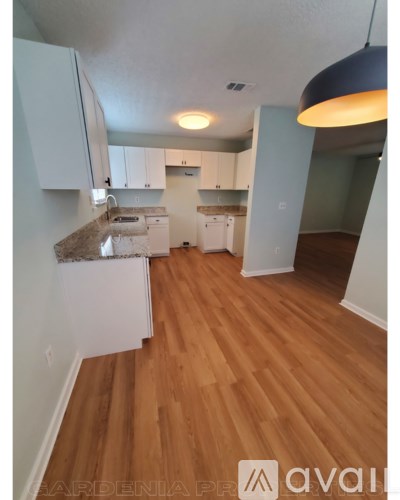 A kitchen with white cabinets and a wooden floor.