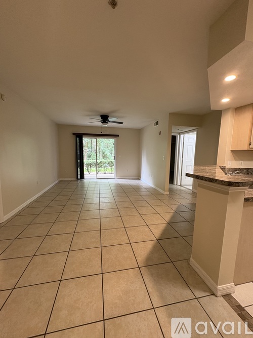 A spacious room with tiled flooring and a ceiling fan.