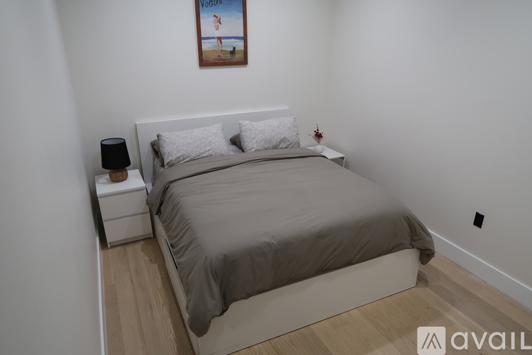 A bedroom with a bed, nightstand, and a painting on the wall.