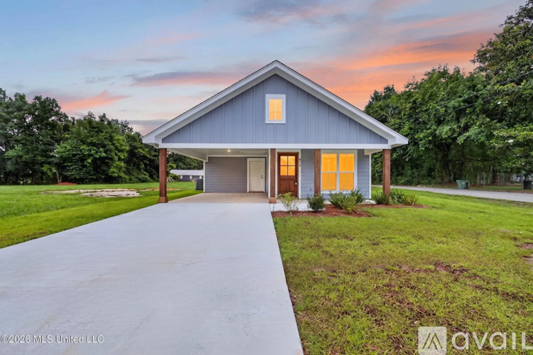 A house with a grey roof and a driveway in front of it.