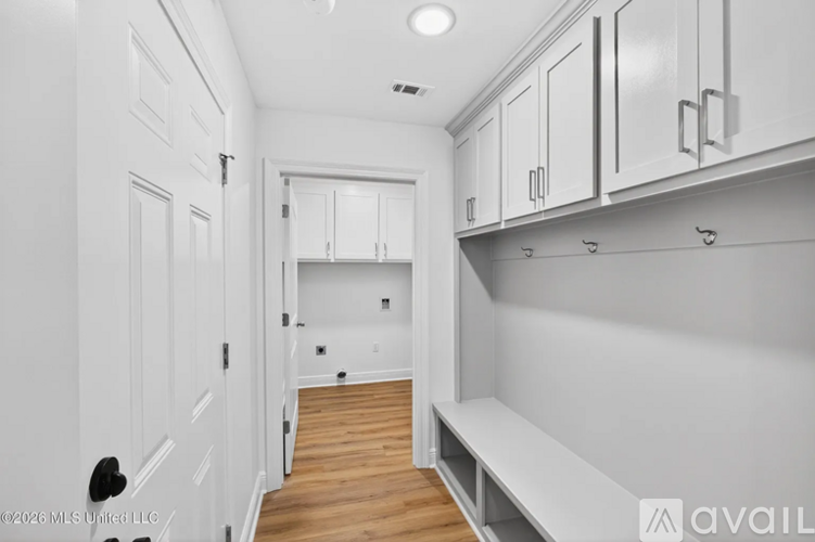 A white interior space with cabinets and a bench.