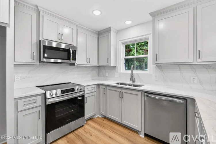 A modern kitchen with white cabinets and stainless steel appliances.