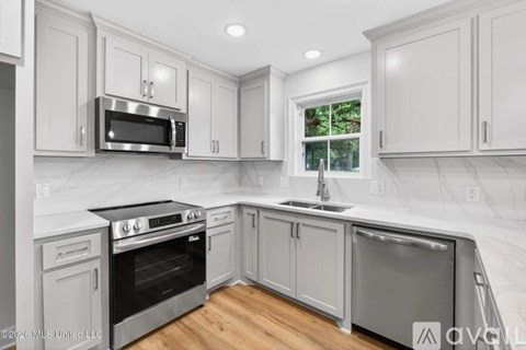 A modern kitchen with white cabinets and stainless steel appliances.