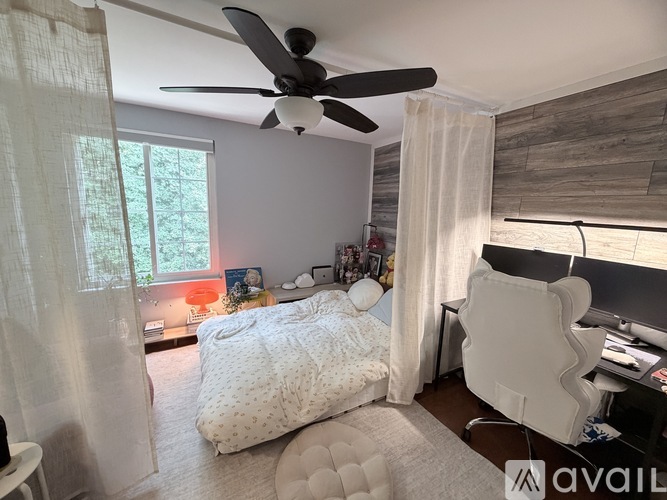 A bedroom with a bed, desk, and ceiling fan.