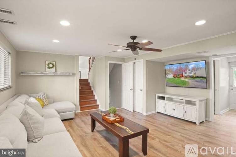 A living room with a white couch and a flat screen TV mounted on the wall.