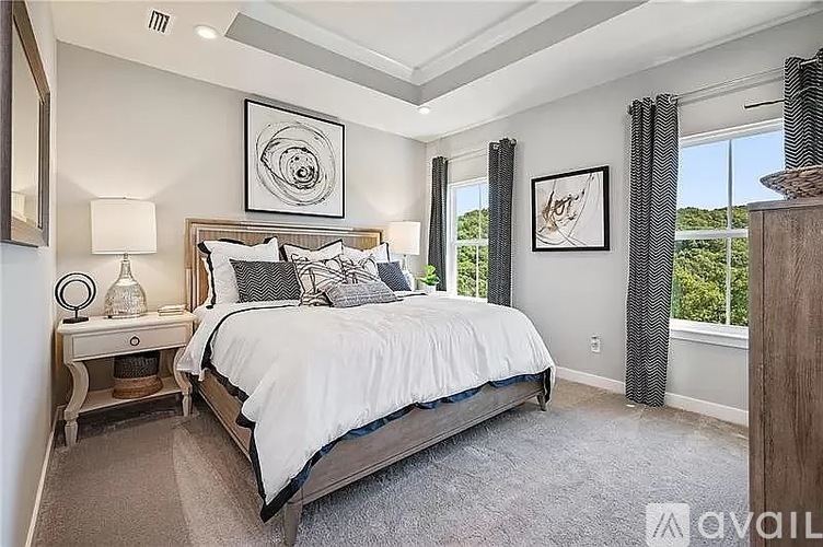 A bedroom with a large bed and a window with curtains.