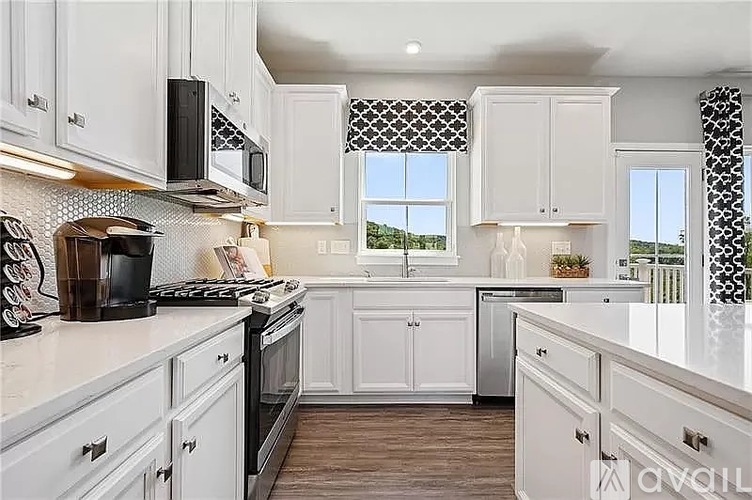 A kitchen with white cabinets and a black microwave.