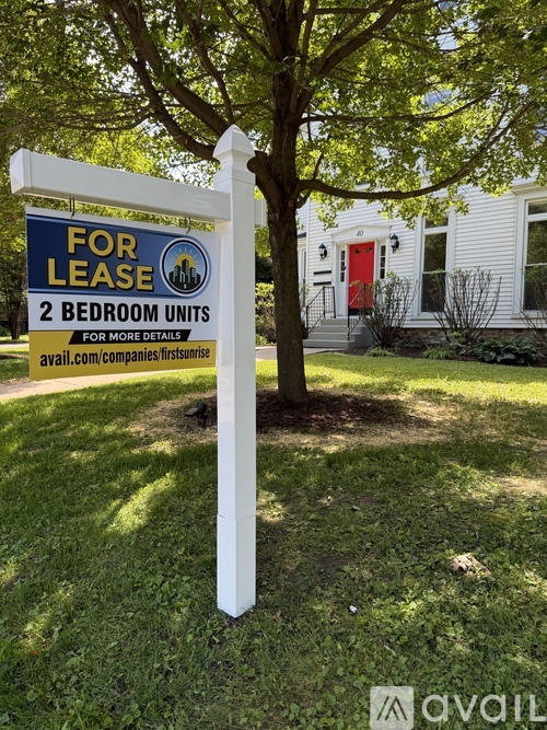 A sign for leasing two bedroom units is displayed in front of a house.