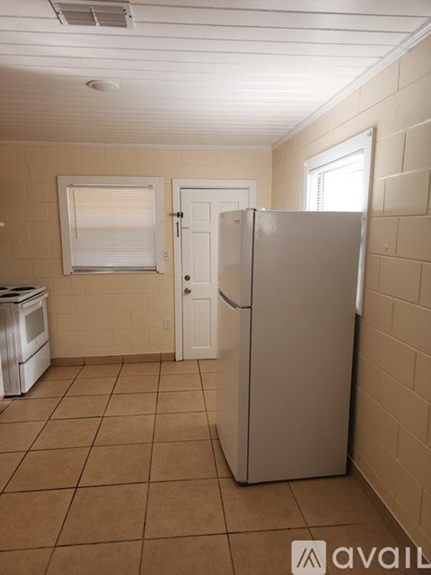 A kitchen with a refrigerator, stove, and window.