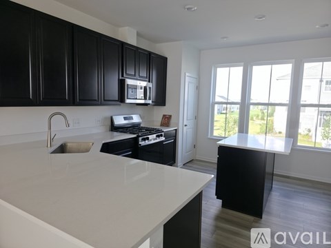 A kitchen with black cabinets and white countertops.