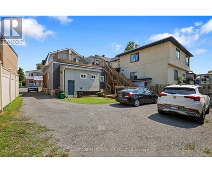 A gravel driveway leads to a two-story house with a garage.