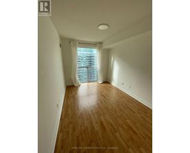 A room with wooden flooring and a window with white curtains.