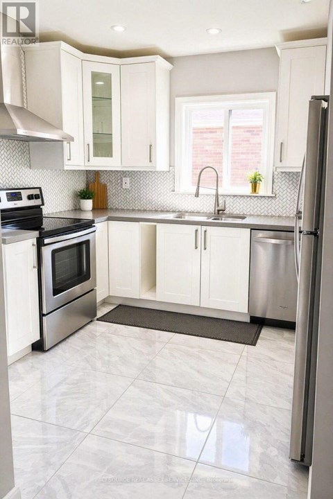 A kitchen with white cabinets and a stainless steel refrigerator.
