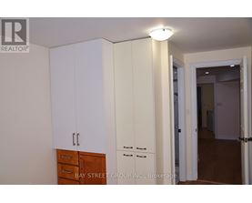 A white cabinet with a drawer is in the foreground of an empty room.