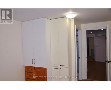 A white cabinet with a drawer is in the foreground of an empty room.