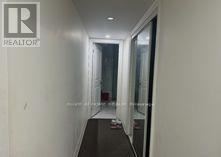 A hallway with a glass door and a white wall.