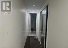 A hallway with a glass door and a white wall.