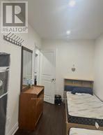 A bedroom with a bed, dresser, and a fridge.