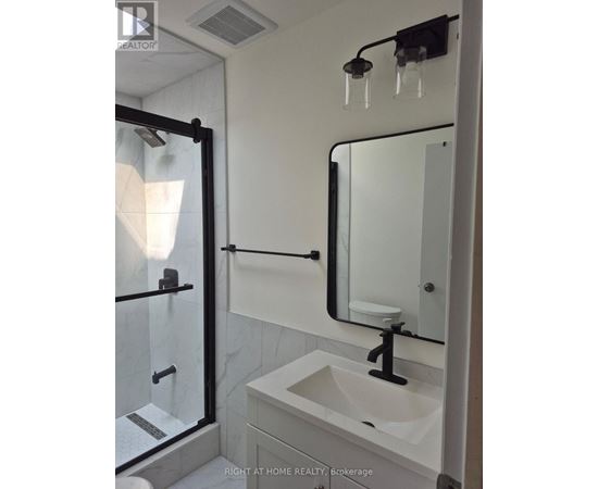 A bathroom with a sink, mirror, and shower.