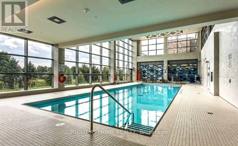 A large indoor swimming pool with a glass wall on one side.