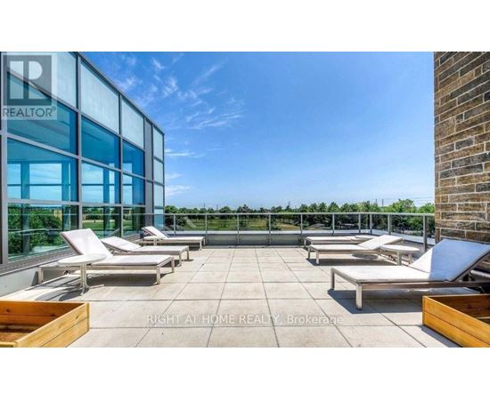 A rooftop patio with lounge chairs and a glass wall.