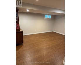 A room with wooden flooring and a window with blinds.