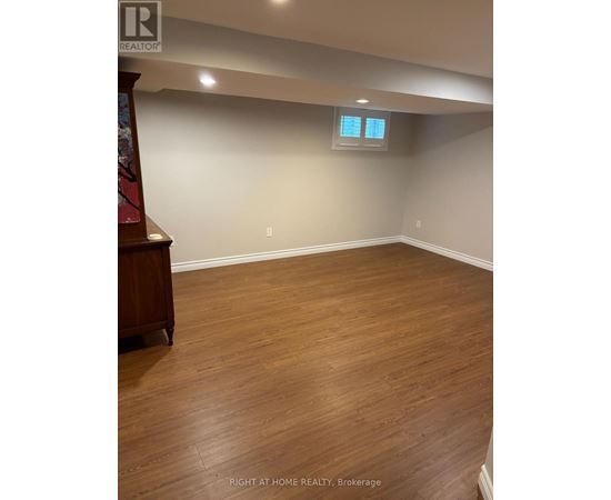 A room with wooden flooring and a window with blinds.