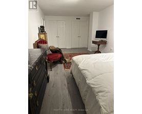 A bedroom with a bed, chair, and a TV stand.