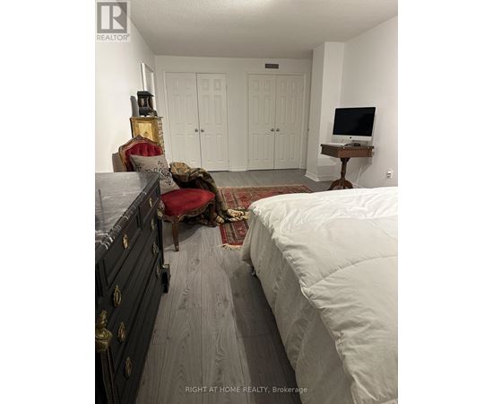 A bedroom with a bed, chair, and a TV stand.