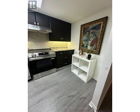 A kitchen with black cabinets and a framed painting on the wall.