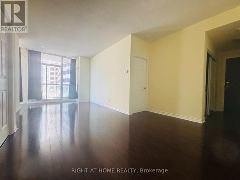A room with wooden floors and white walls, with a door on the right side.