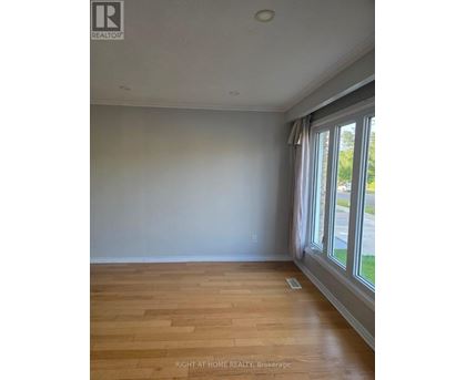 A room with wooden flooring and a window with curtains.