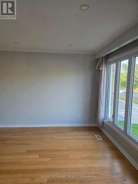 A room with wooden flooring and a window with curtains.