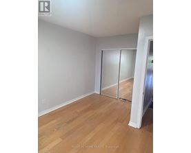 A room with wooden flooring and a white wall with a sliding door.