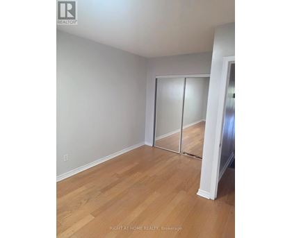 A room with wooden flooring and a white wall with a sliding door.